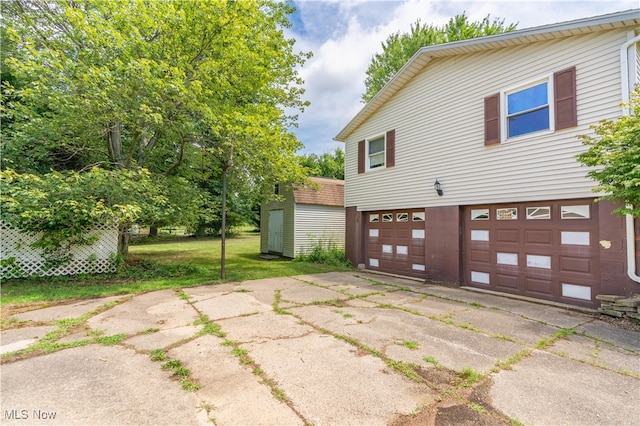 view of property exterior featuring a lawn, a shed, and a garage