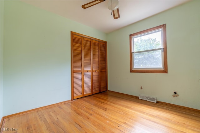 unfurnished bedroom featuring light hardwood / wood-style floors, ceiling fan, and a closet