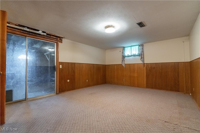 carpeted spare room with wood walls and a textured ceiling