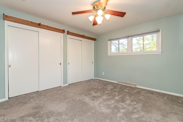 unfurnished bedroom with ceiling fan, light carpet, and two closets