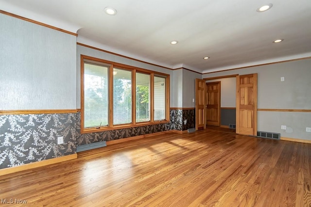 empty room featuring crown molding, a baseboard heating unit, and hardwood / wood-style flooring