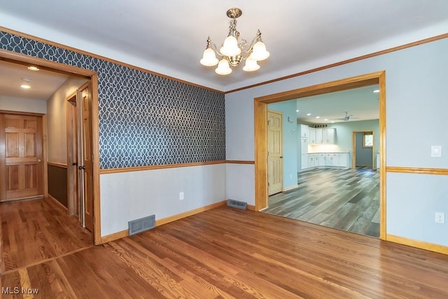 empty room with hardwood / wood-style flooring and a notable chandelier