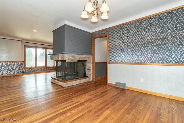 unfurnished living room with a fireplace, an inviting chandelier, light hardwood / wood-style flooring, and ornamental molding