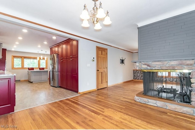 interior space with a fireplace, light hardwood / wood-style floors, crown molding, and a notable chandelier