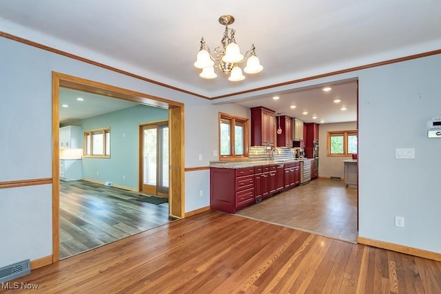 kitchen featuring decorative backsplash, dark wood-type flooring, decorative light fixtures, and a notable chandelier