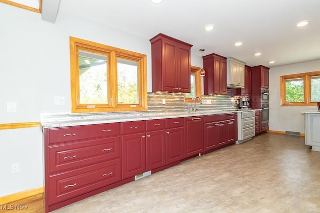 kitchen with pendant lighting, sink, double oven, and tasteful backsplash