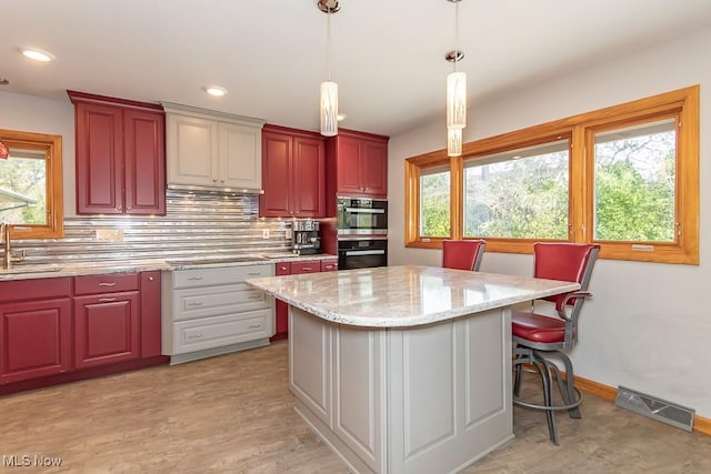 kitchen featuring a center island, sink, tasteful backsplash, double oven, and pendant lighting