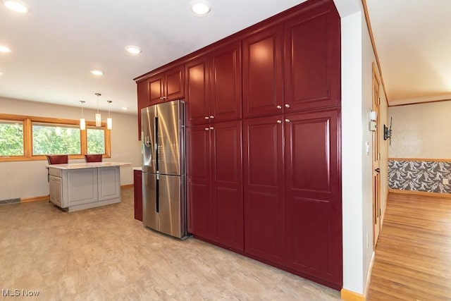 kitchen with a center island, stainless steel fridge, light wood-type flooring, and pendant lighting