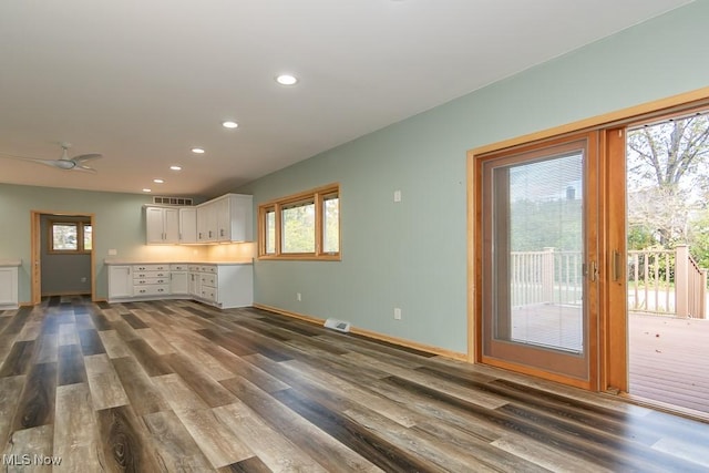 unfurnished living room with ceiling fan and dark wood-type flooring