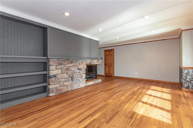 unfurnished living room with crown molding, light wood-type flooring, and a fireplace