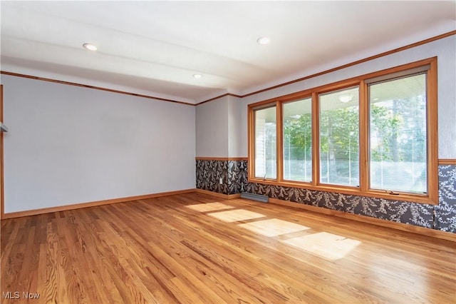 empty room featuring crown molding and light hardwood / wood-style flooring