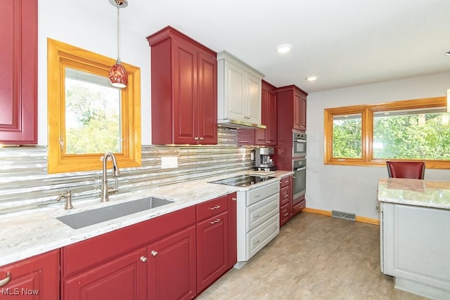 kitchen featuring sink, hanging light fixtures, light hardwood / wood-style flooring, black electric cooktop, and tasteful backsplash