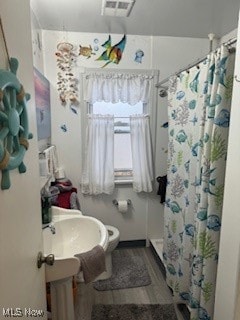 bathroom featuring a shower with shower curtain, hardwood / wood-style flooring, and toilet