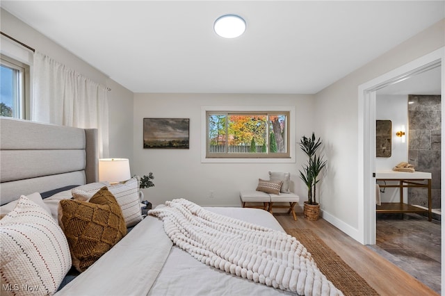 bedroom featuring ensuite bath and light wood-type flooring