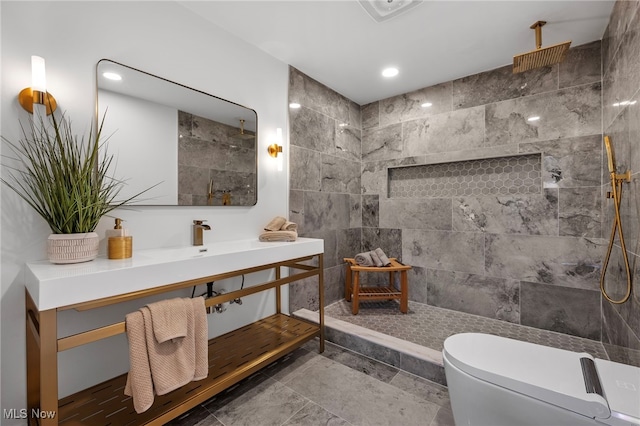 bathroom with toilet, vanity, and a tile shower