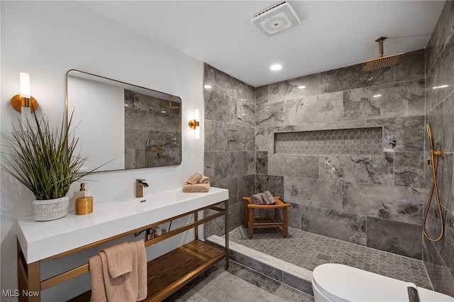 bathroom featuring toilet, vanity, and a tile shower