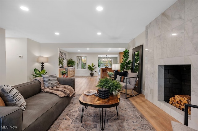 living room with a fireplace, light hardwood / wood-style floors, and a chandelier