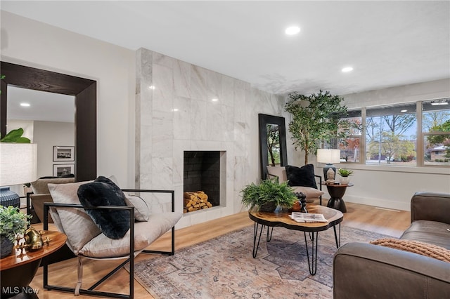 living room with a tile fireplace and light wood-type flooring