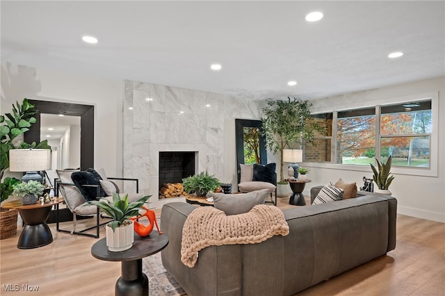 living room with a high end fireplace and light hardwood / wood-style flooring