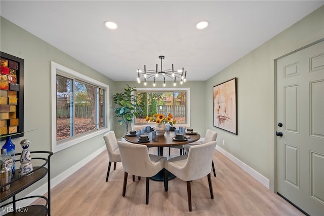 dining space with light hardwood / wood-style floors, plenty of natural light, and a notable chandelier