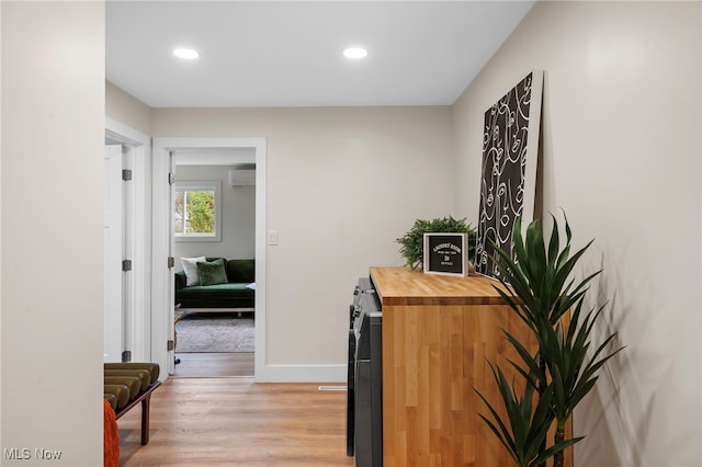 corridor featuring light hardwood / wood-style floors and an AC wall unit