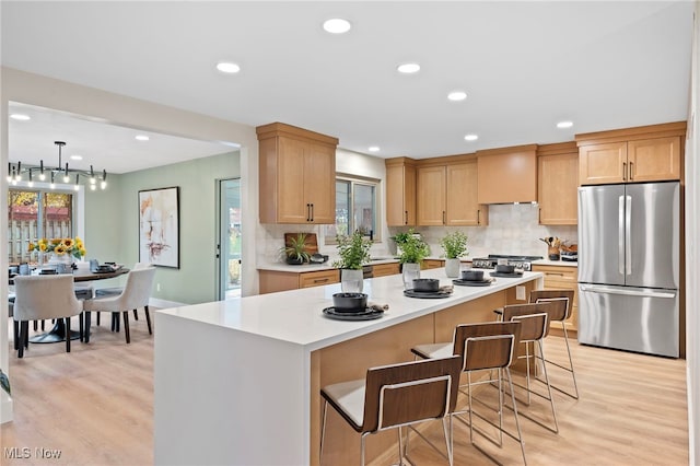 kitchen with appliances with stainless steel finishes, tasteful backsplash, custom exhaust hood, a kitchen island, and light wood-type flooring