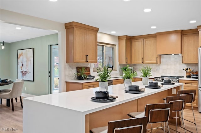 kitchen with a kitchen bar, plenty of natural light, light wood-type flooring, and a kitchen island