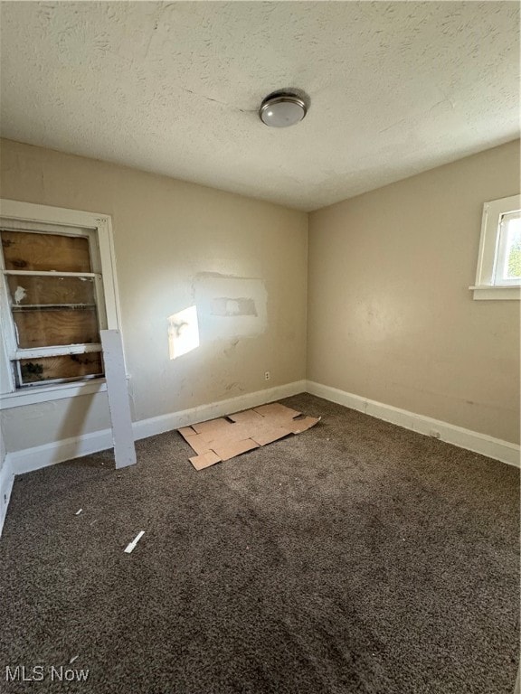 empty room featuring dark colored carpet and a textured ceiling