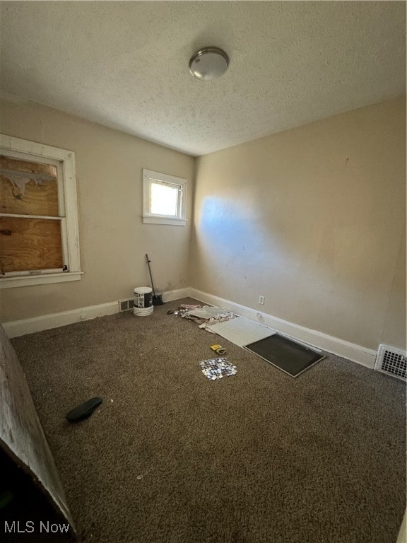 carpeted empty room featuring a textured ceiling