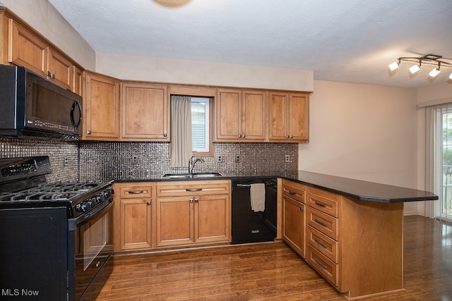 kitchen with tasteful backsplash, kitchen peninsula, sink, and black appliances