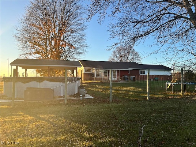 back house at dusk with a yard and a trampoline