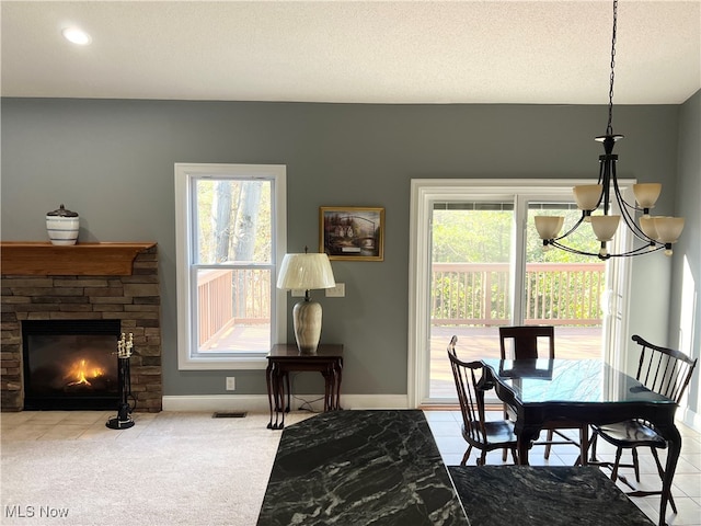 carpeted dining space featuring a textured ceiling, a healthy amount of sunlight, a fireplace, and an inviting chandelier