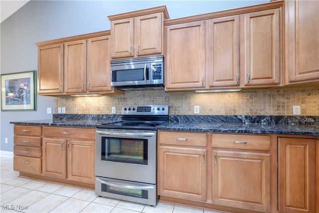 kitchen featuring appliances with stainless steel finishes, backsplash, light tile patterned floors, and dark stone counters