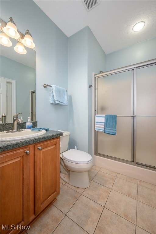 bathroom featuring tile patterned flooring, vanity, toilet, and walk in shower