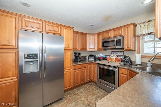 kitchen featuring a textured ceiling, sink, and appliances with stainless steel finishes