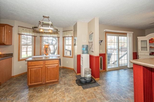 kitchen with an inviting chandelier, hanging light fixtures, a textured ceiling, and a center island