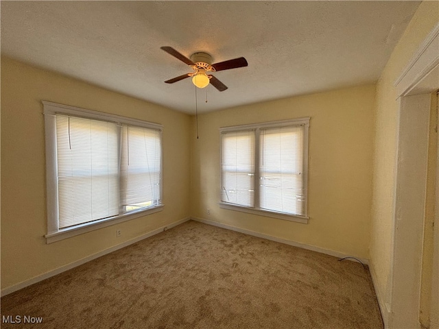 carpeted spare room featuring ceiling fan, a healthy amount of sunlight, and a textured ceiling