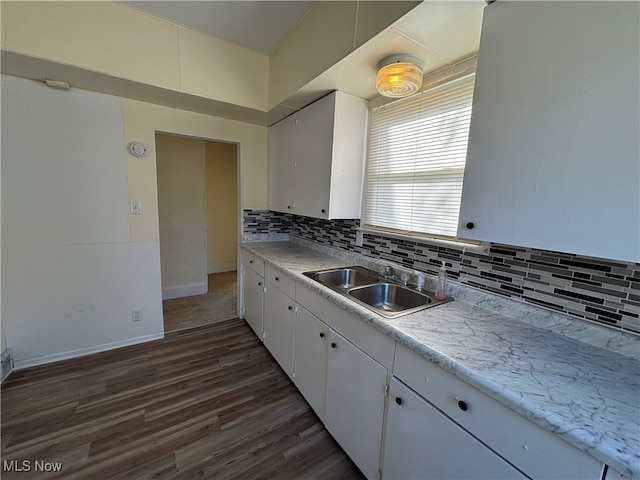 kitchen with dark wood-type flooring, backsplash, sink, and white cabinets