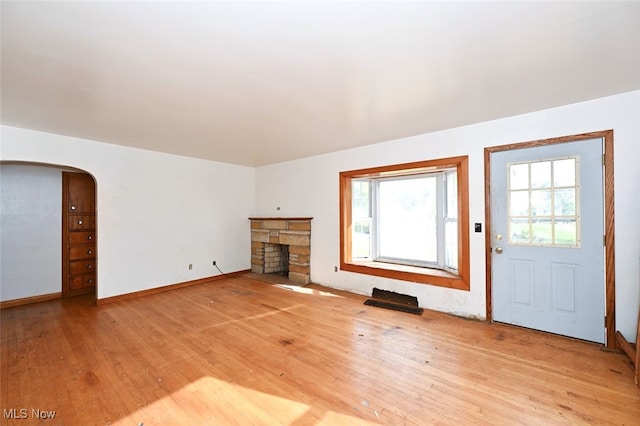 unfurnished living room featuring light hardwood / wood-style floors and a stone fireplace