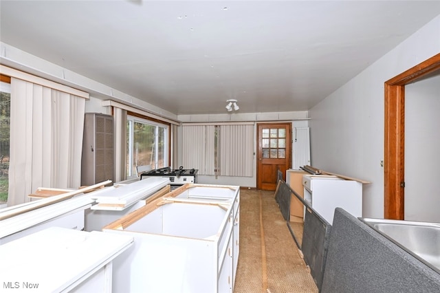 kitchen with a kitchen island, white cabinetry, and light colored carpet