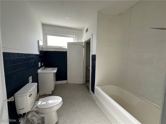 bathroom with vanity, a bath, tile patterned floors, toilet, and tile walls