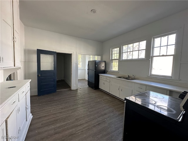 kitchen featuring black fridge, white cabinets, sink, dark hardwood / wood-style floors, and electric range