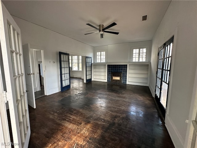 unfurnished living room with french doors, plenty of natural light, dark hardwood / wood-style floors, and a tile fireplace