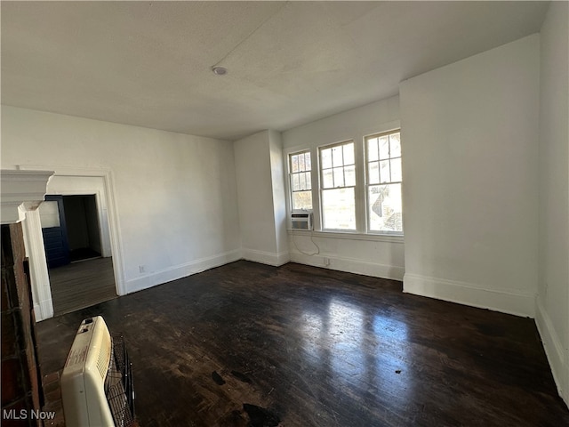 spare room with dark wood-type flooring, heating unit, and a textured ceiling