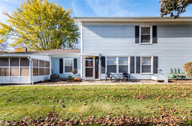 rear view of house featuring central AC unit, a sunroom, and a yard