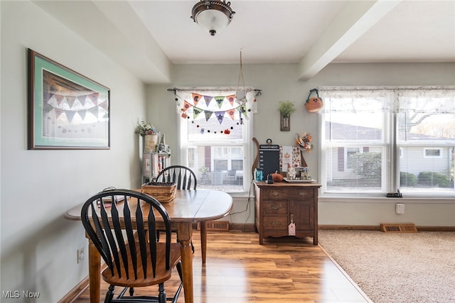 dining area featuring light hardwood / wood-style flooring and beamed ceiling