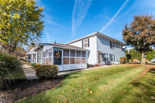 back of house featuring a lawn and a sunroom