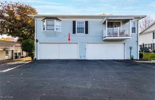 view of front of home with a garage, central AC, and a balcony