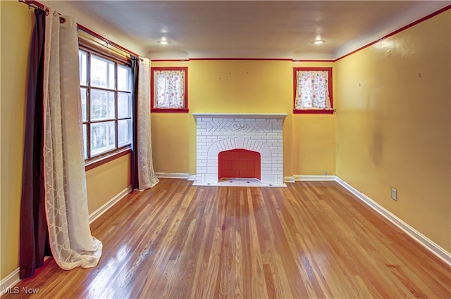 unfurnished living room featuring wood-type flooring, ornamental molding, and a fireplace