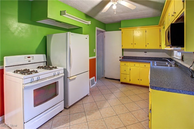 kitchen with a textured ceiling, light tile patterned floors, sink, white appliances, and ceiling fan